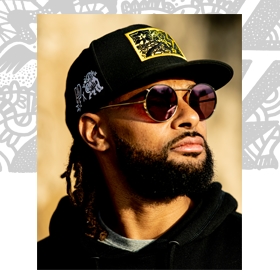 Patty Mills wearing a hat designed by Nabor Etienne for the Patty Mills x Tap Pilam San Antonio Spurs capsule collection
