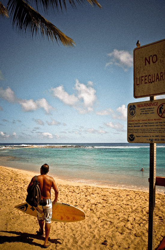 Surfer heads to the beach in Kauai, Hawaii - photographed by Justin Winget
